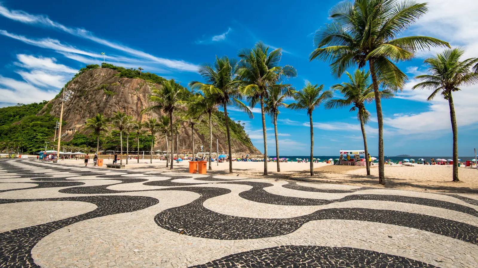 Calçadão de ondas em pedra portuguesa e coqueiros na Praia de Copacabana